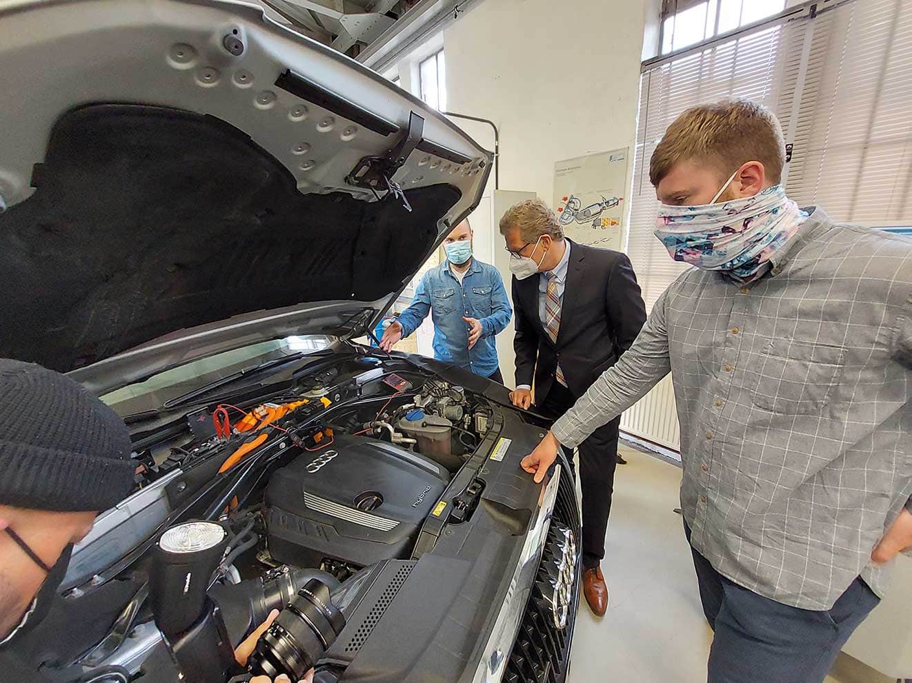 Sie sind Mangelware: Die beiden Studierenden im Masterstudiengang in der beruflichen Fachrichtung Fahrzeugtechnik Nicolay Tank (vorne rechts) und Tim Tilger (hinten links). Wirtschaftsminister Dr. Bernd Buchholz lässt sich von ihnen das Innere eines Hybrid-Fahrzeugs erklären.