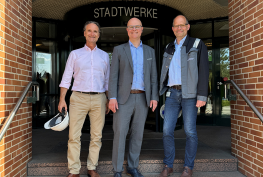 3 Personen vor dem Eingang der Stadtwerke Flensburg.