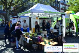Erster Flensburger Nachhaltigkeitsmarkt hier der Stand des Klimapaktes Flensburg mit Personen vor und hinter dem Stand.