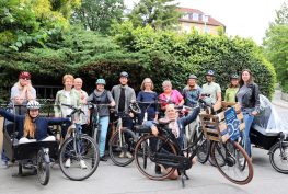 Eine Gruppe Menschen auf und neben Fahrrädern draußen.